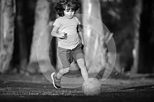 Boy child playing football on football field. Kid playing soccer. Young sporty kids.