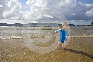 Boy child playing in fun beach water waves photo