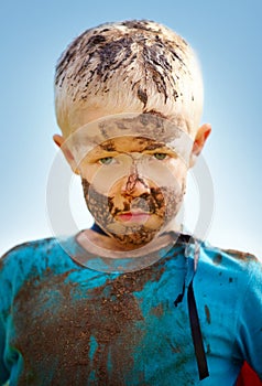 Boy, child and portrait with mud on face from playing, dirt or naughty in summer weather or water. Kid, person or grime