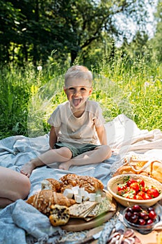 Boy child preschooler on a picnic. Smiles, eating cherries and enjoying summer.