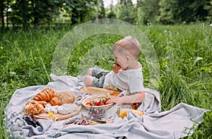 Boy child preschooler on a picnic. Smiles, eating cherries and enjoying summer.