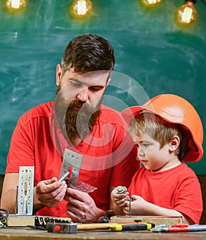 Boy, child in protective helmet makes by hand, repairing, does crafts with dad. Father with beard and little son in