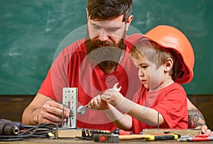 Boy, child in protective helmet makes by hand, repairing, does crafts with dad. Father with beard and little son in