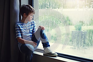 Boy child, rain and sad by window with thinking, mental health and space for mockup in home. Male kid, raining and think