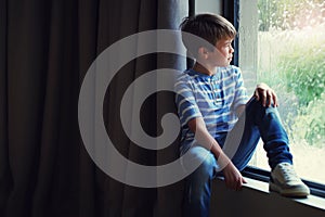 Boy child, rain and thinking by window with sad face, mental health and mockup space in home. Male kid, raining and