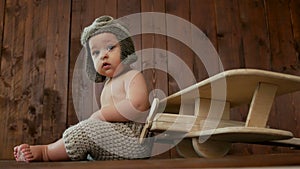 Boy child sitting next to a wooden plane toy