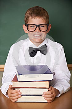 Boy child, smile and portrait with books, classroom and learning for exam, assessment and studying for knowledge