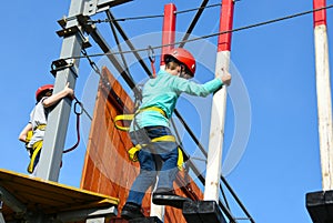 Boy child steps on wooden boards on the obstacle course in an amusement park, outdoor activities, rock climbing, danger, training,