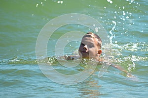 Boy child swim in sea. A boy swims in the open ocean. Learning to swim in the salty sea. Summer vacation in the tropics.