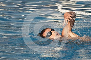 Boy child swimmer swim in outdoor swimming pool. Professional young athlete training front crawl technique. Water sports