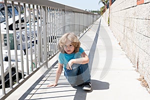 Boy child take short break hunkering down on promenade, rest