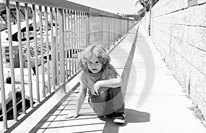 Boy child take short break hunkering down on promenade, rest