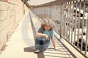 Boy child take short break hunkering down on promenade, rest