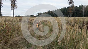 Boy child in a yellow vest and red hat runs