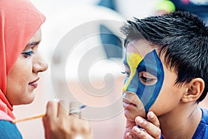 Boy child young having his face painted for fun at a birthday party