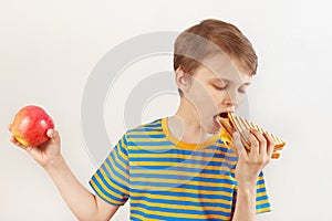 Boy chooses between sandwich and healthy diet on white background