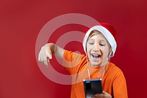 A boy in a Christmas hat holds a phone in front of him and dances from seeing a message on Christmas