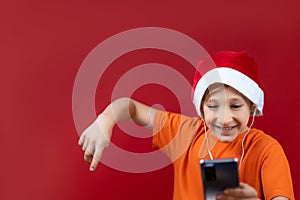 A boy in a Christmas hat holds a phone in front of him and dances from seeing a message on Christmas