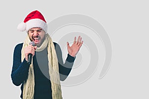 Boy in a Christmas hat Rocking Out. Image of a handsome man singing to the microphone, isolated on light. Emotional