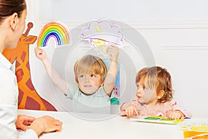 Boy in class show weather cards with rain, storm and rainbow