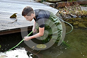 Boy cleaning garden pond