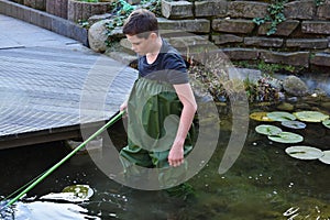 Boy cleaning garden pond