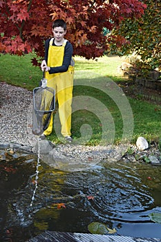 Boy cleaning garden pond