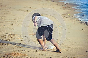 Boy is cleaning up garbage on the beach for enviromental clean up concept