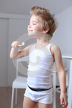 Boy cleans his teeth in the morning and plays with a toothbrush