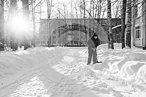 A boy cleans snow near the house on a sunny day