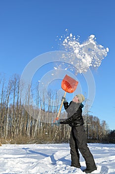 Boy in clearing in winter woods vigorously tosses photo