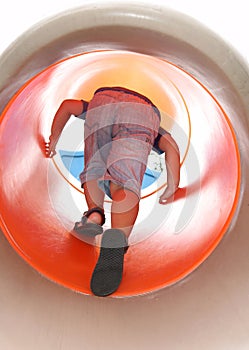 Boy clibming up on a cylindric slide