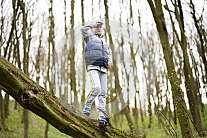 Boy climbed a felled tree in spring forest. Happy childhood moments