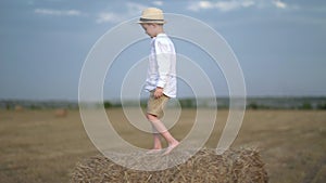 The boy climbed on a haystack and has fun