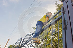 The boy climbed onto the fence. The child climbs on the gate, fe