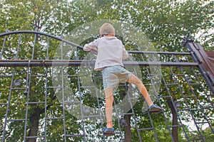 The boy climbed onto the fence. The child climbs on the gate, fe