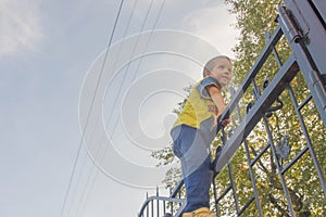 The boy climbed onto the fence. The child climbs on the gate, fe