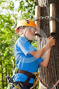 Boy with climber equipment intently keeps rope