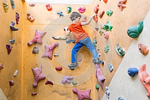 Boy climbing on artificial boulders wall in gym