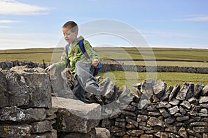 Boy climbing dry-wall in English countryside