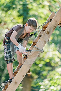 Boy climbing ladder with equipment in adventure rope park