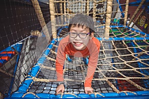 Boy climbing the net at indoor playground and smiles