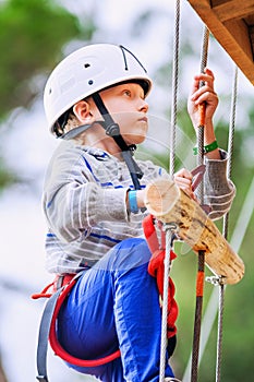 Boy climbing rope-ladder in adrenalin park