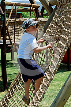 Boy climbing a rope ladder in playground