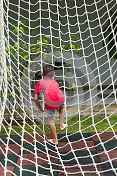 Boy climbing a rope net on the playground.