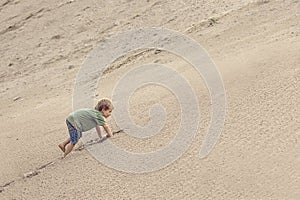 Boy Climbing On The Sand dune. Summer day