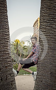 Boy climbing between tow palm tree's