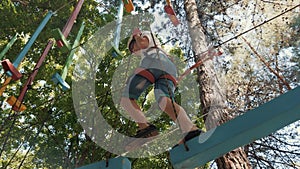 The boy climbs the obstacle course in the camp. A brave boy fulfills the Boy Scout standards