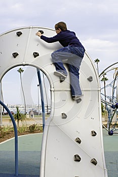 Boy climbs playground equipment