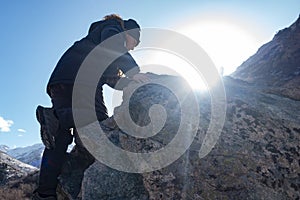 Boy climbs a rock against the snow winter mountains. Children rock climbing. Extreme hobby trains